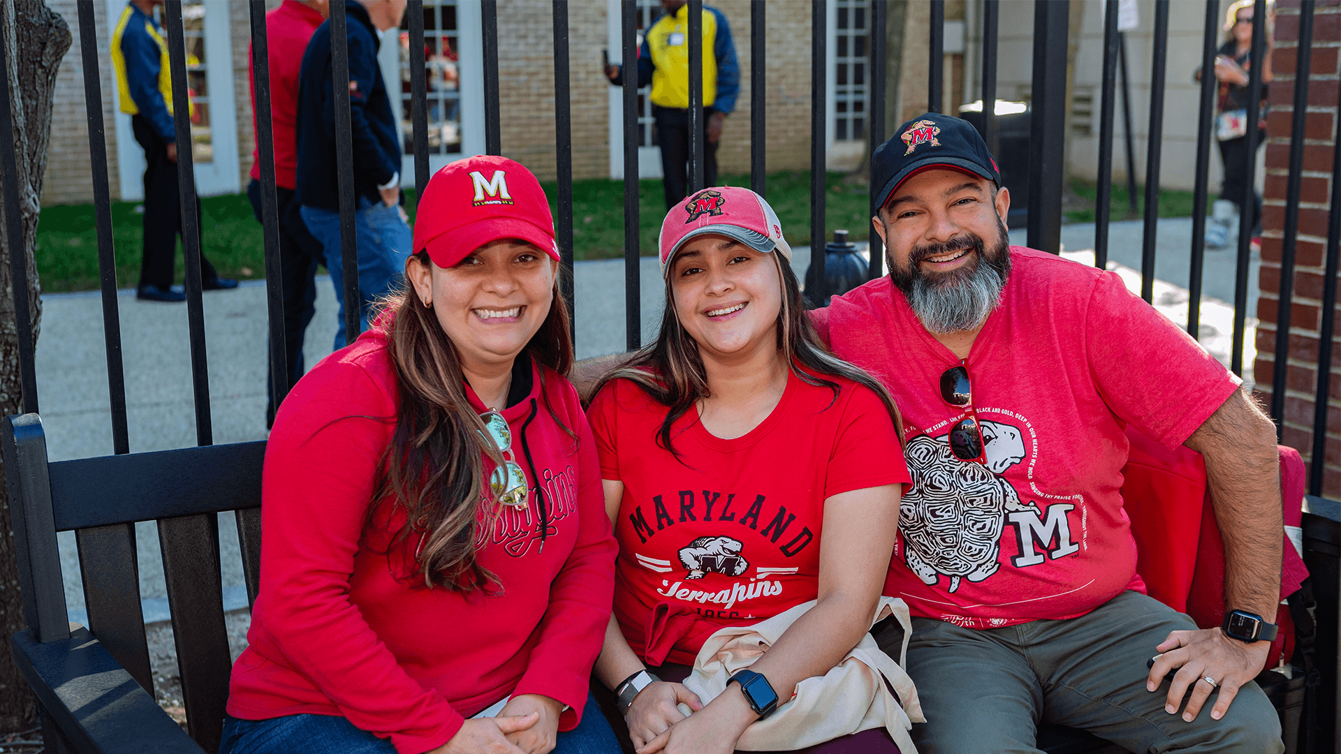 Three Maryland graduates decked out in red enjoy the Alumni Tailgate and Beer Garden at Riggs Alumni Center.