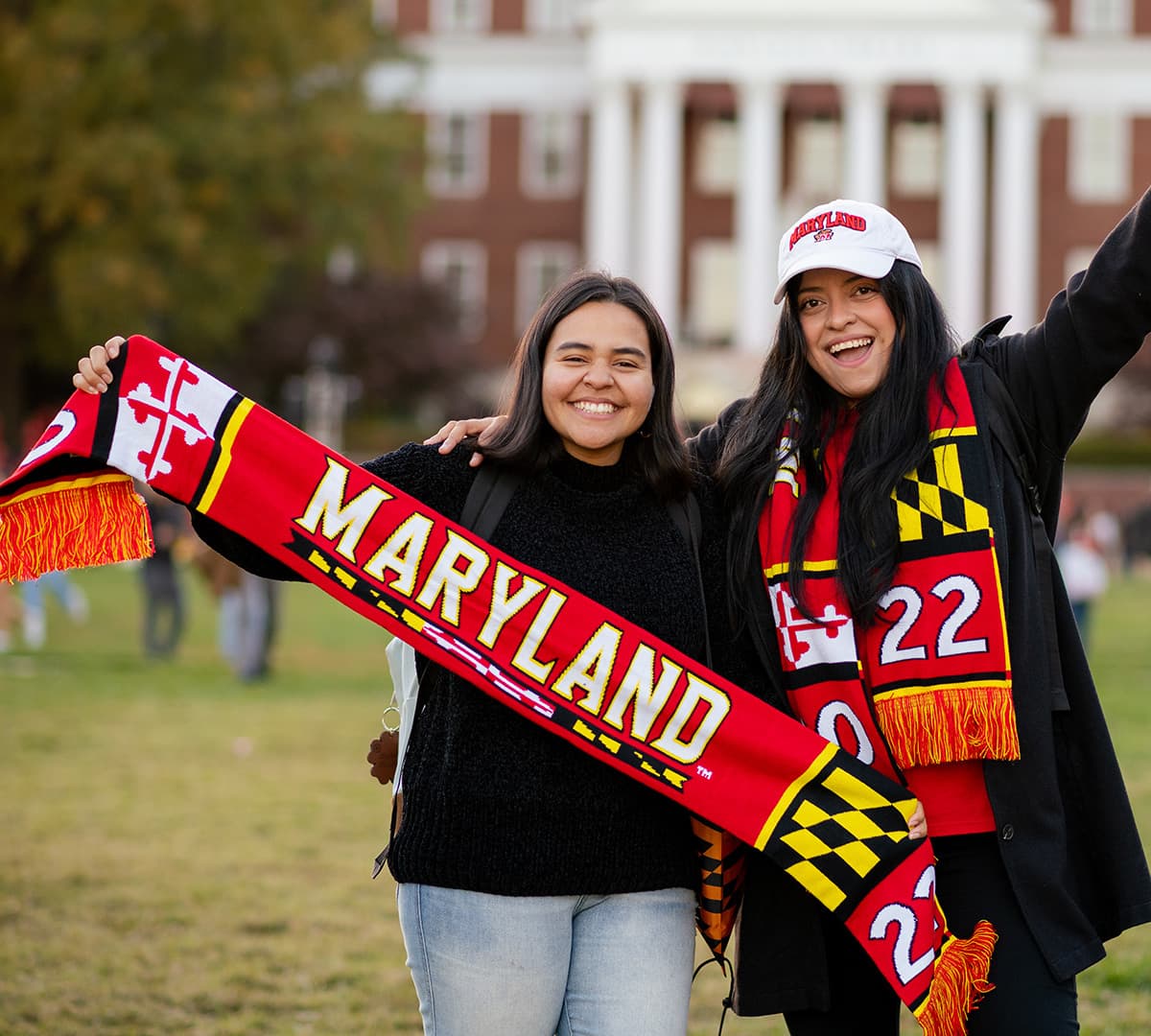 Two students celebrate receiving a limited-edition Homecoming scarf at Terp Carnival.