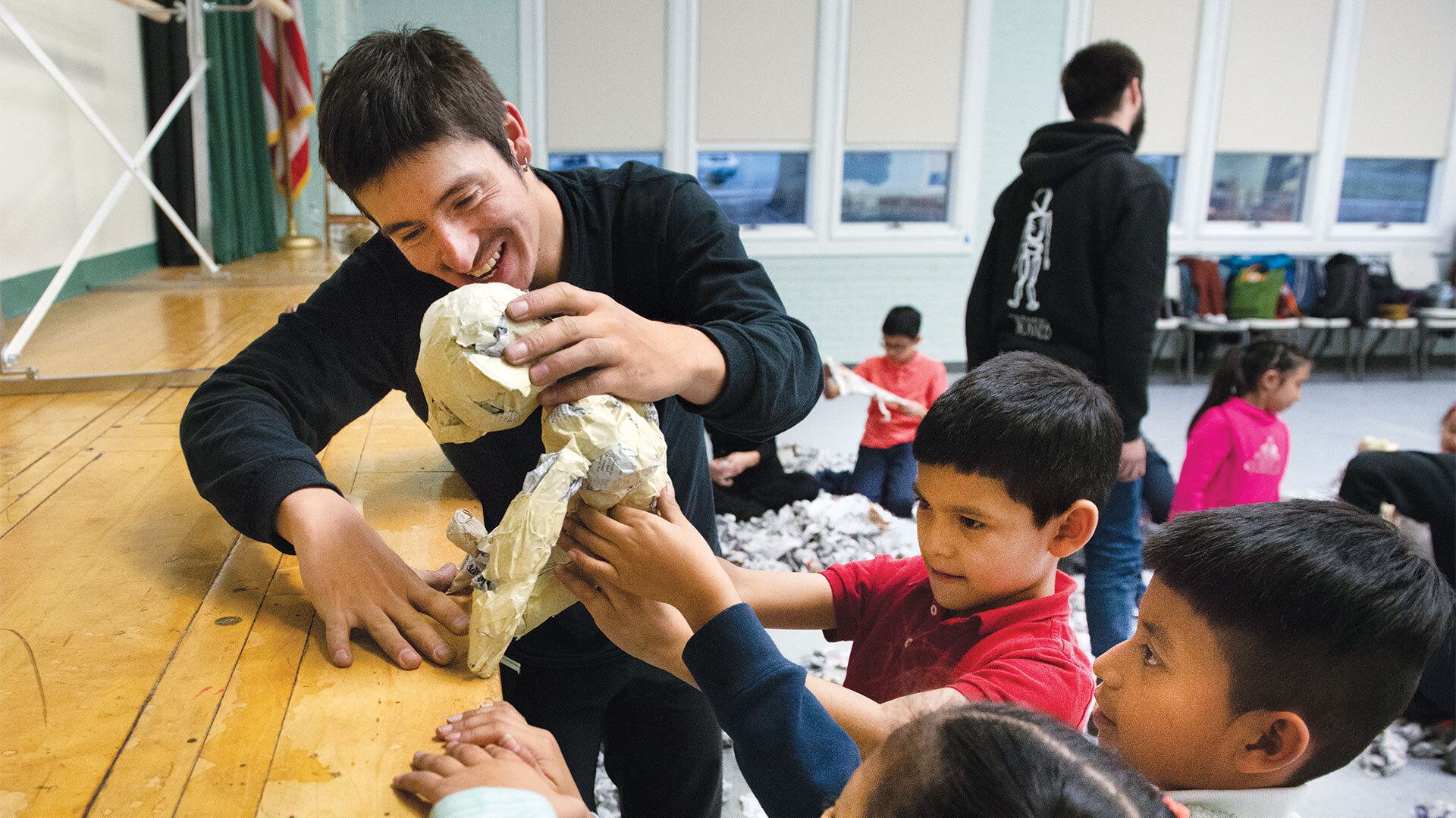 man helps kids work with puppet