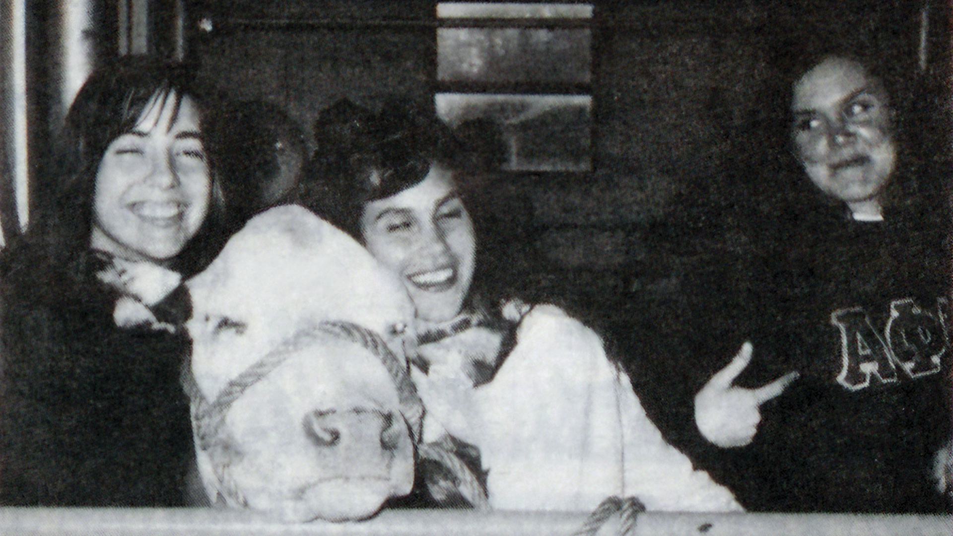 three women smile with cow
