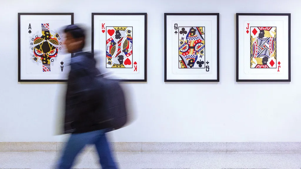 student walks by four framed images of playing cards