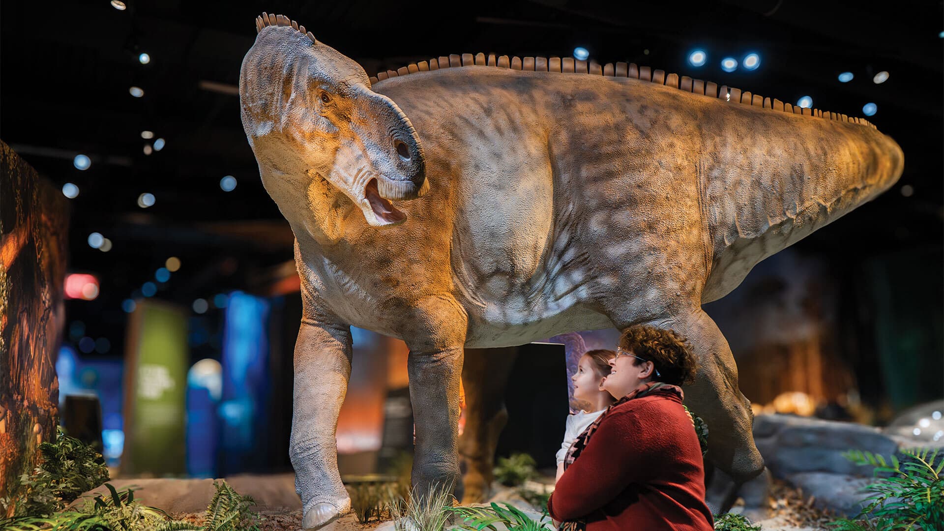 mom and daughter look at dinosaur at museum