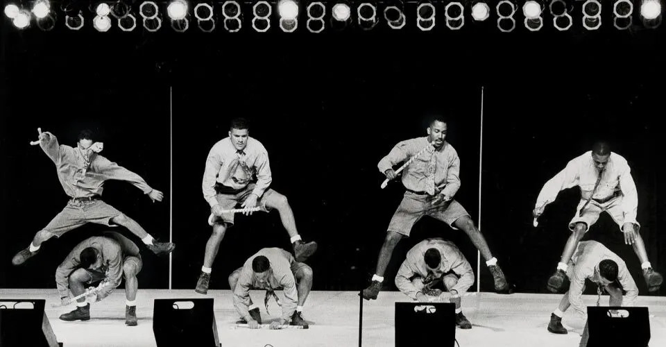 four students leap over another four students on stage during step show