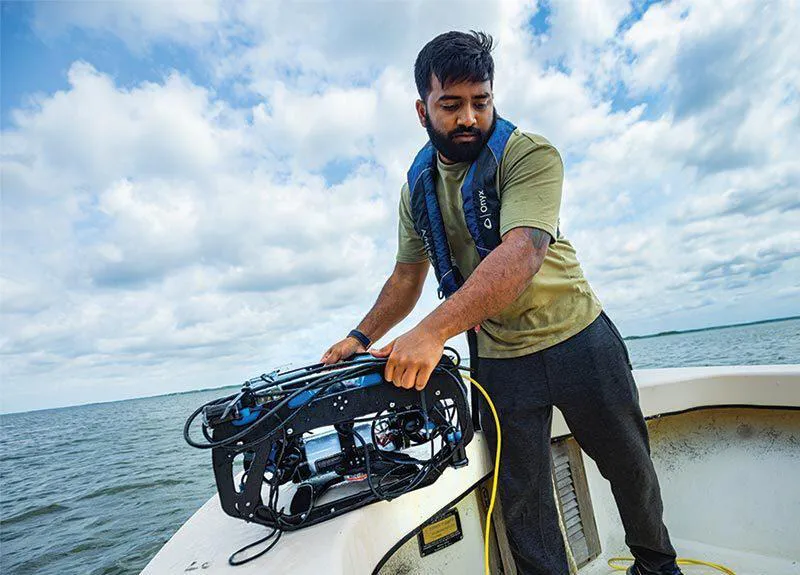 Keshav Rajasekaran Ph.D. ’22 prepares to launch an underwater robot to seek oysters.
