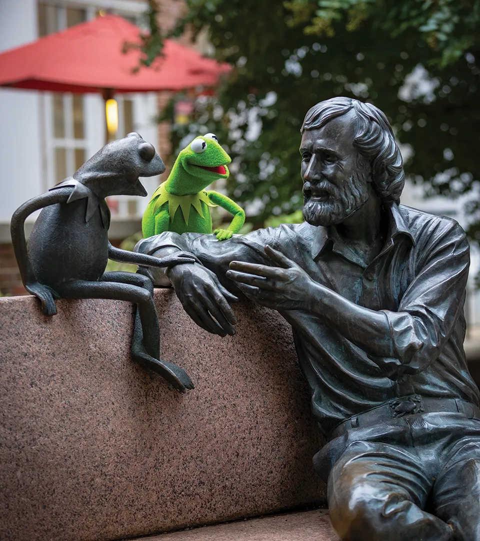 Kermit sits with statue of himself and Jim Henson on UMD campus
