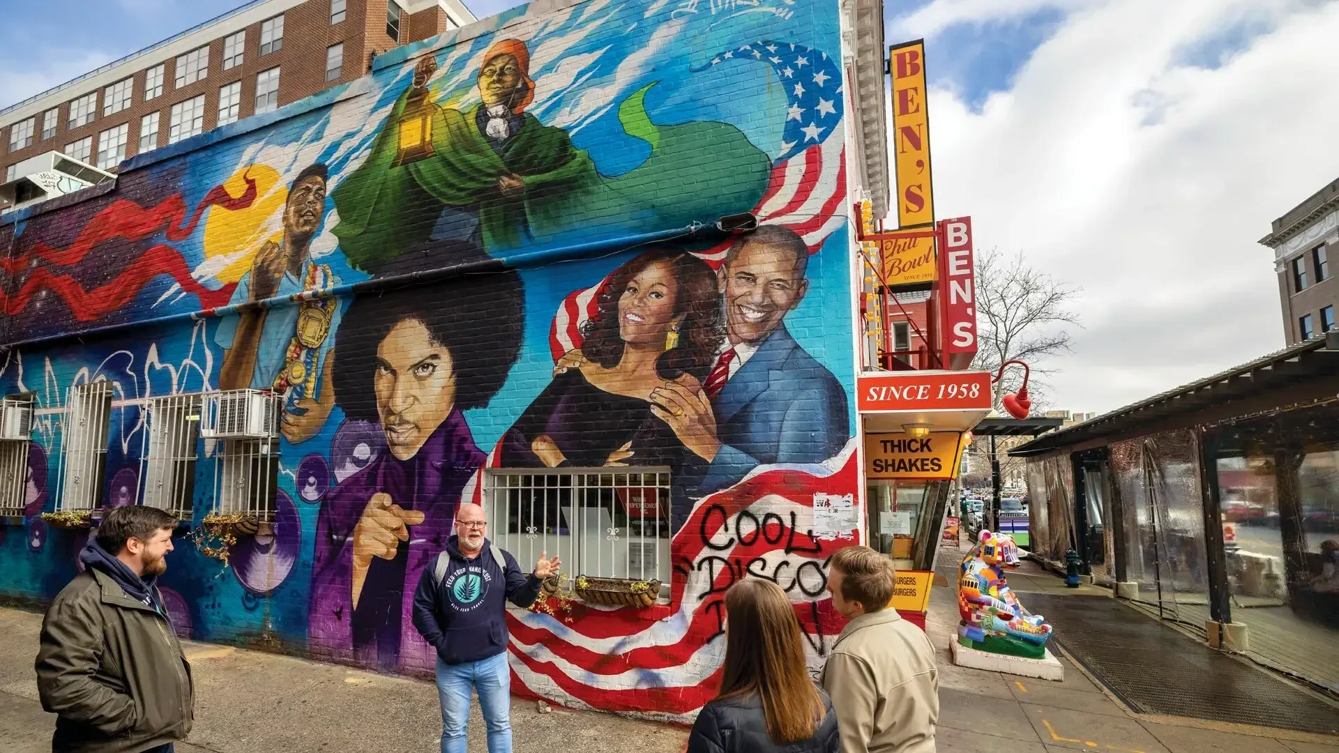 People chatting on the street with a wall covered with cartoons in the background