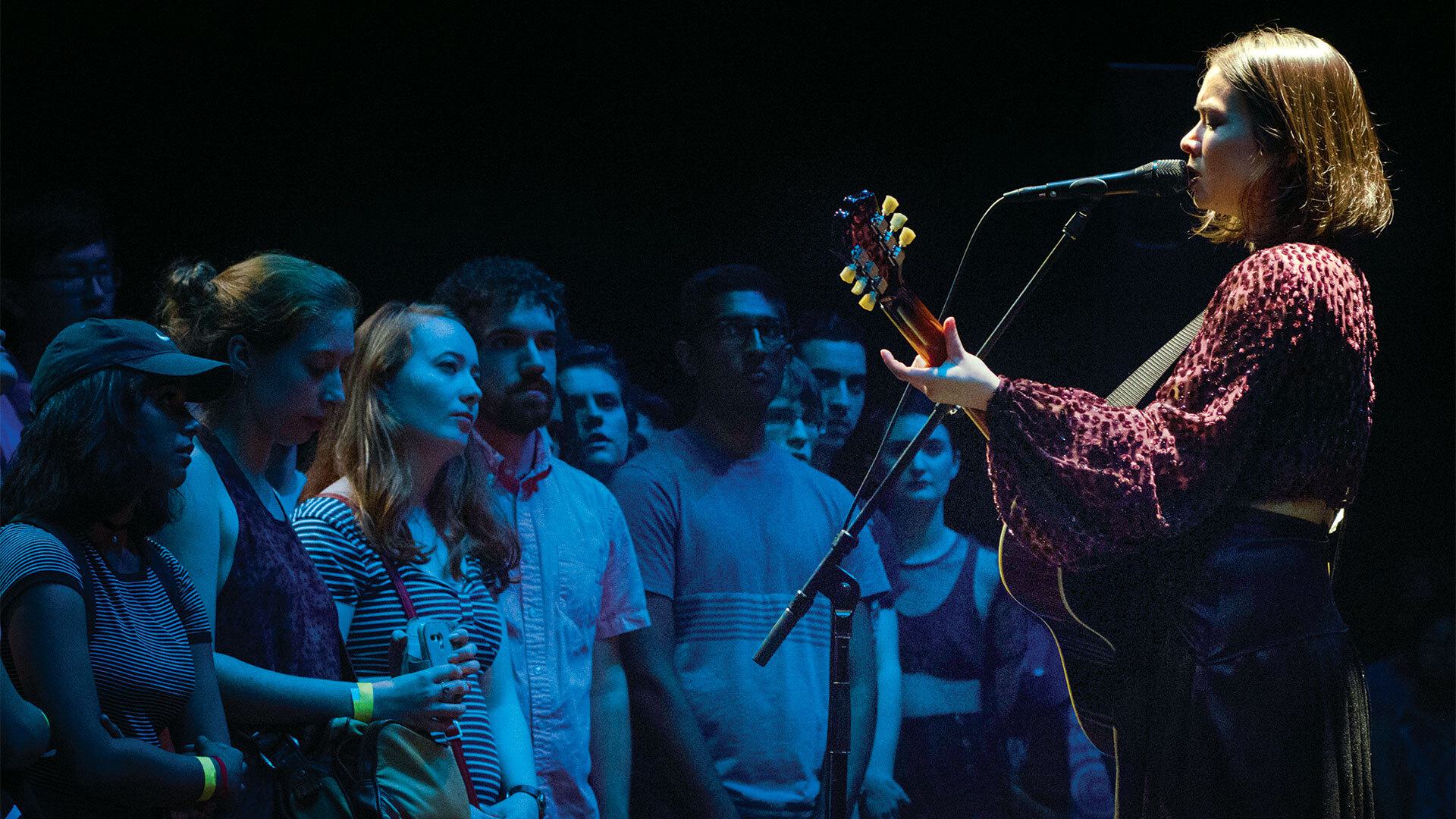 singer plays guitar while performing for crowd
