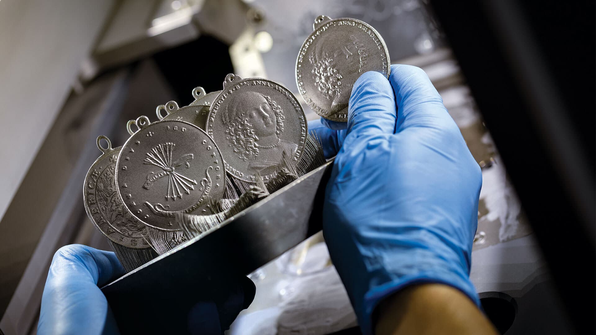 gloved hands hold 3D-printed peace medals