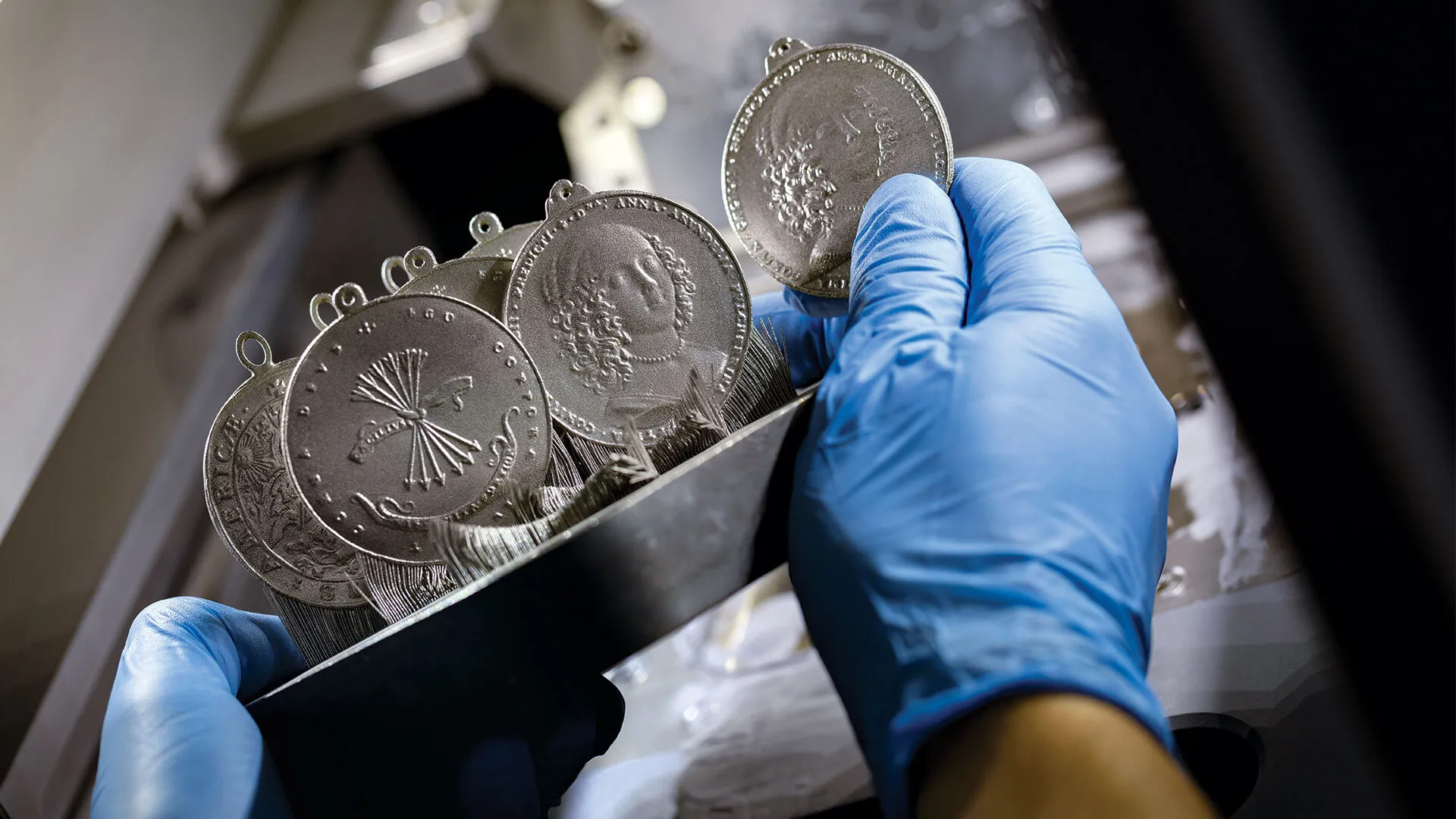 gloved hands hold 3D-printed peace medals