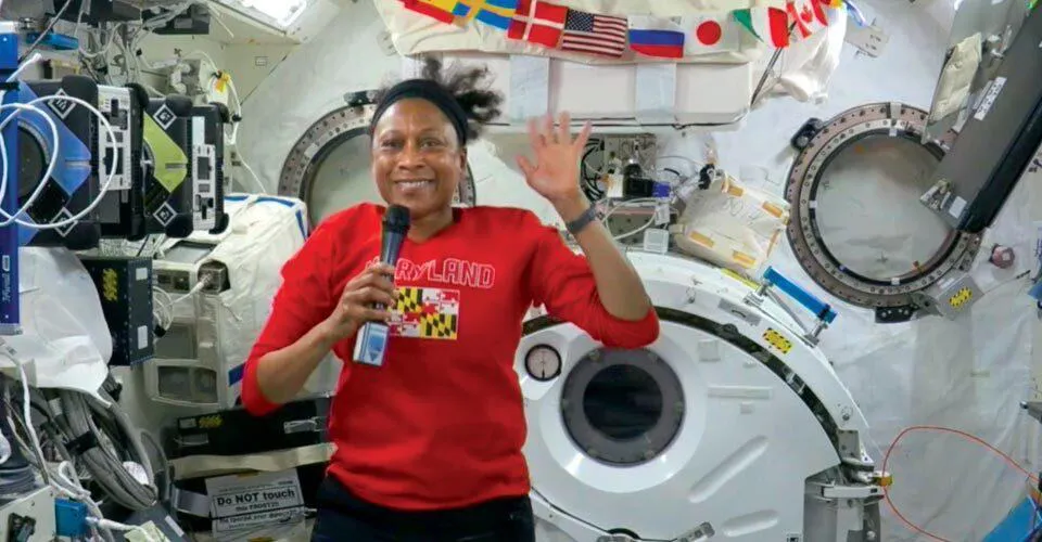 Jeanette Epps waves from ISS while wearing red Maryland shirt