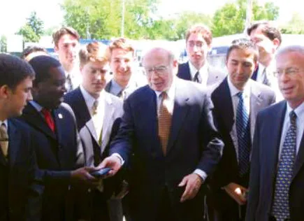 Warren Buffett hands student wallet, with David Kass smirking on the right