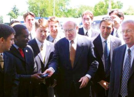 Warren Buffett hands student wallet, with David Kass smirking on the right