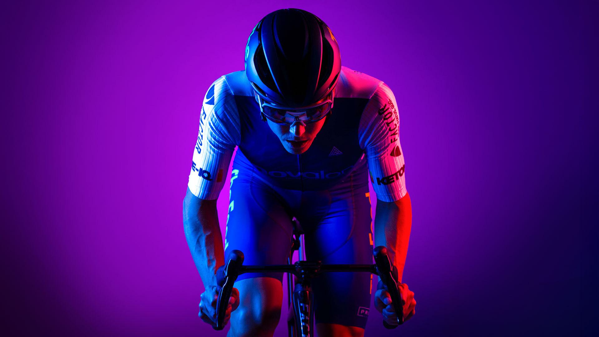 Ryan Collins poses on bike, with purple background