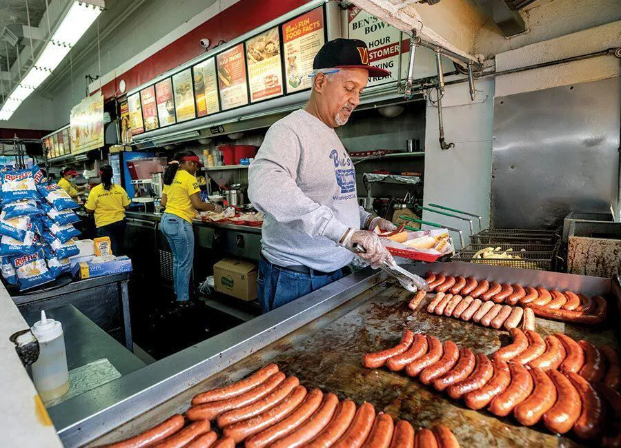 man flips sausages on grill