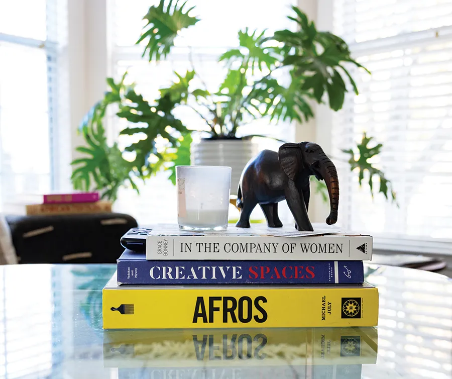 stack of three books with candle and elephant figurine on top and plant in background