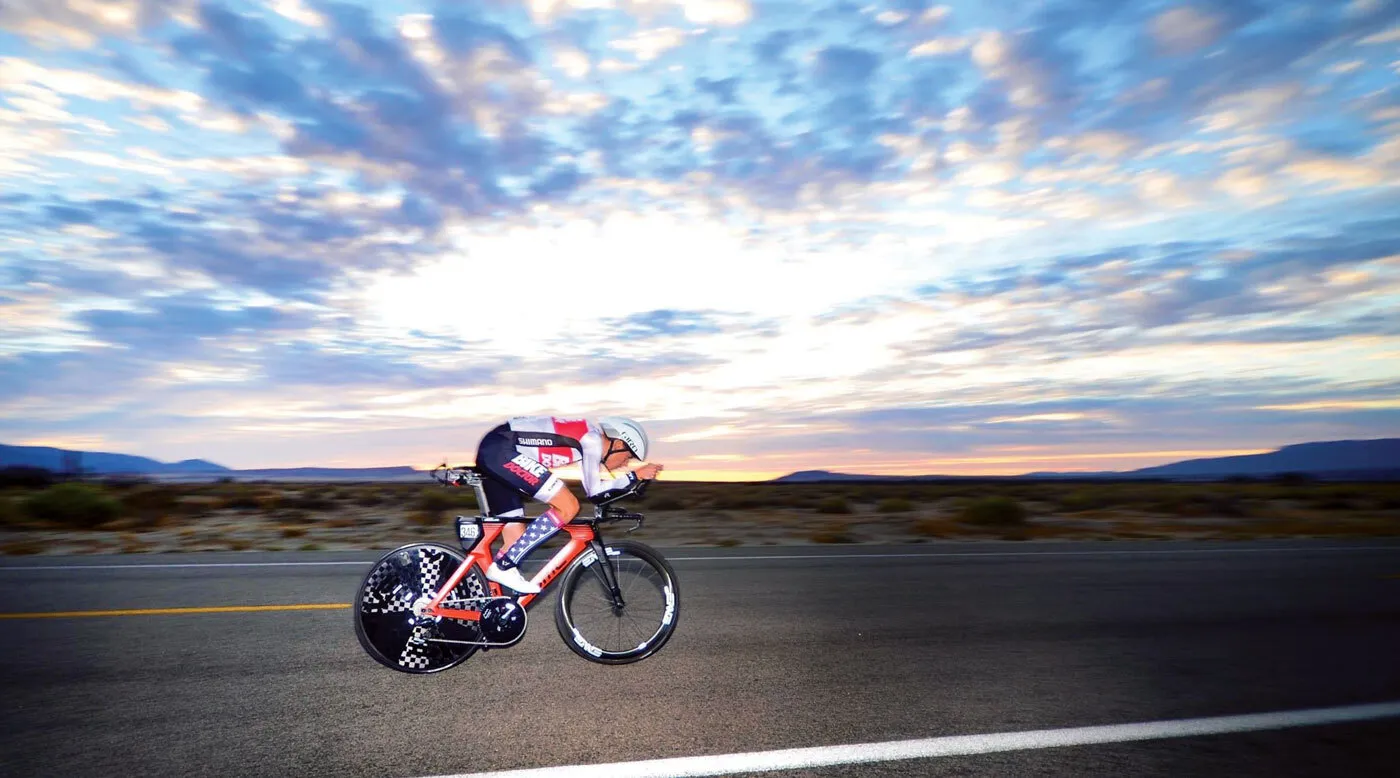 Ryan Collins bikes along road with sunset in background