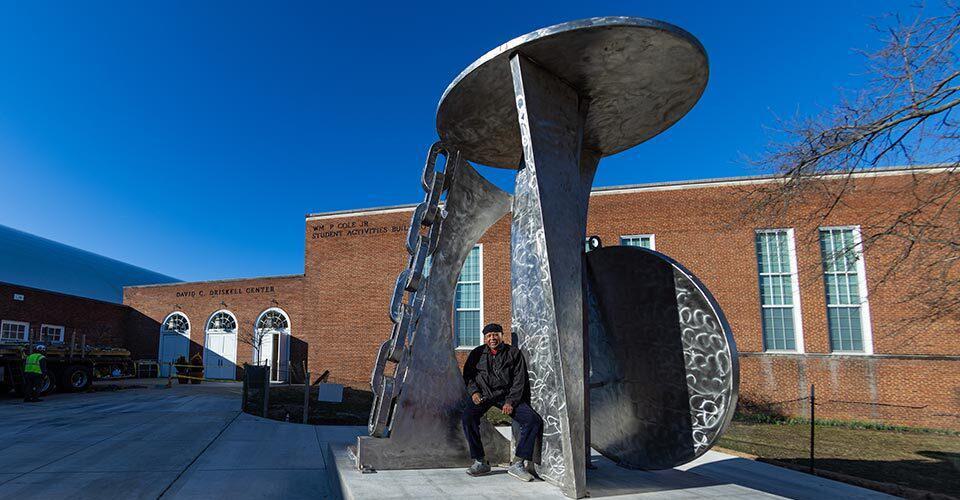 Melvin Edwards poses with statue