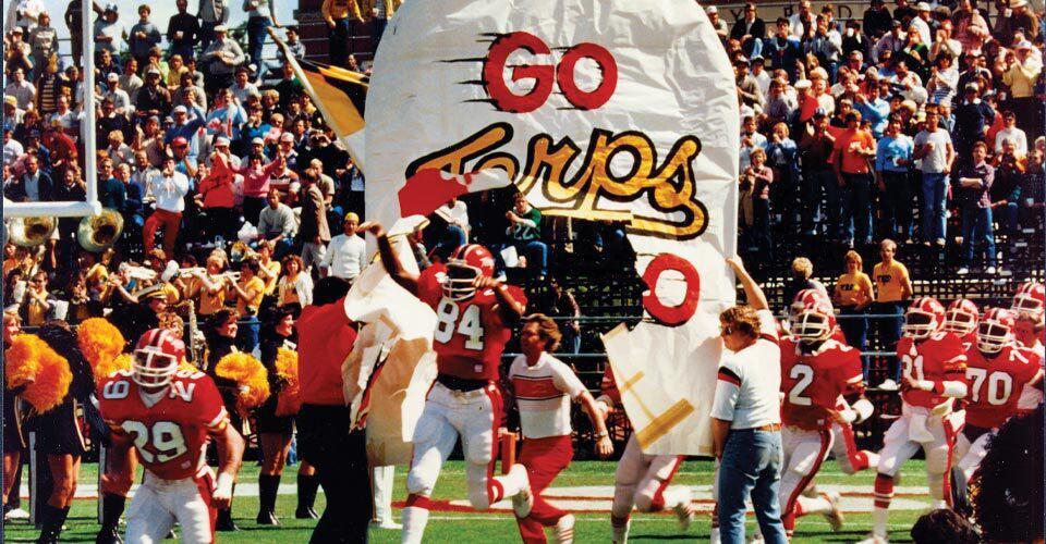 football team runs through "Go Terps" banner
